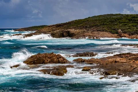 Powerful ocean waves crash dramatically against a rugged rocky coastline Foto stock