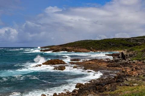 Powerful ocean waves crash dramatically against a rugged rocky coastline Stock Photos