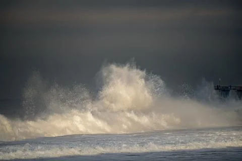 Powerful ocean waves crash dramatically against the shore under a stormy sky Photos