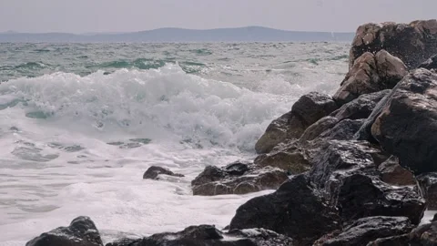 Powerful ocean waves crash violently against dark rocky coastal shores Stock Footage 337417887
