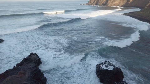 Powerful ocean waves crashing on big rocks at wild volcanic beach during sunset Video stock 122972168
