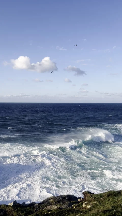 Powerful ocean waves hit rocky cliffs near coastal promenade at sunset Stock Footage 314372468
