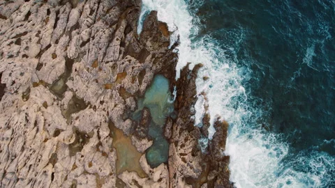 Powerful ocean waves meet rock formations in overhead aerial top down view Stock Footage 320088579