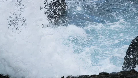 Powerful ocean waves surging through rugged black volcanic rocks and filling a Vidéo 345831352