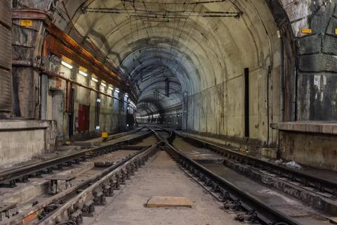 A powerful perspective shot of intersecting train tracks inside a grimy, illu Fotos Stock
