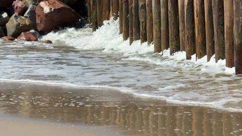 Powerful sea waves crash against weathered wooden breakwater posts along the sho 스톡 동영상 310833193