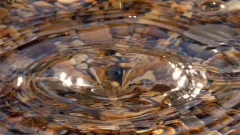 Powerful splash of seldom dripping in shallow pure water with pebble bottom Stock Footage 98095670