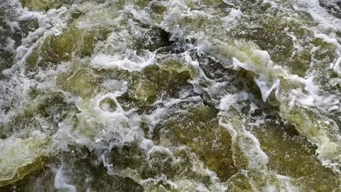 Powerful stream of gray-green water foaming in mountain river. Video stock 163357377