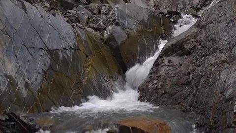 Powerful stream of water flowing down steep wet rocks in the Caucasus Mountains, Stock Footage 325819680