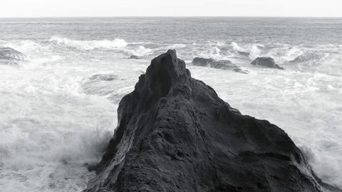 Powerful tide foaming wave sparkling to big rock in black and white tone Stock Footage 128946109