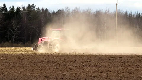 Powerful tractor with a plow drives through dusty and arid farmland in hot Video stock 130247835