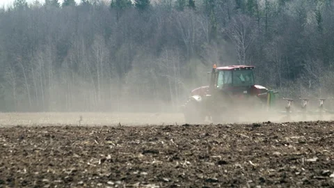 Powerful tractor with a plow drives through dusty and arid farmland in hot Stock Footage 130301516