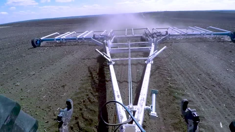 A powerful tractor pulls the harrow. A tractor cultivating a field in spring. Stock Footage 273083495