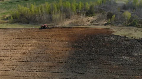 Powerful tractor in red with plow, working, plowing, treatment of dark soil Stock Footage 108664373