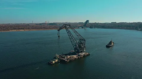 Powerful tugboat pulling large floating crane by river to city of shipbuilders Stock Footage 176313607