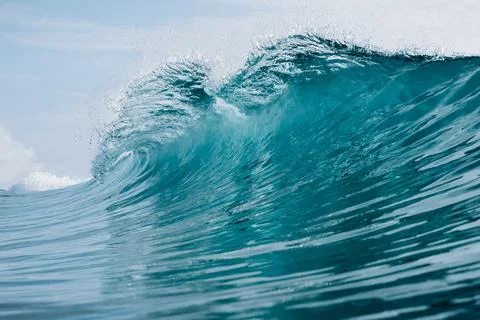 Powerful turquoise ocean wave breaking under blue sky, crashing barrel wave Stock Photos