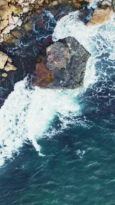 Powerful turquoise waves crash against rugged coastal rocks in a dramatic t.. Stock Footage 341548197