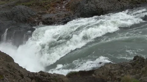 Powerful water cascades over volcanic basalt rock formations in a wild Icelandic Stock Footage 346325876