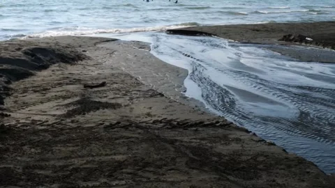 Powerful water current merging with ocean, transforming sandy shoreline through Vidéo 301918670