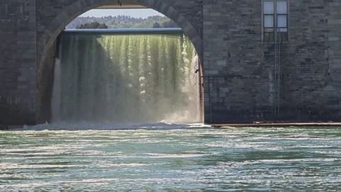 Powerful water dam overflow under a masonry archway on a sunny day Stock Footage 339175385