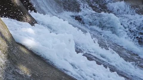 Powerful water rushing over concrete floodgate spillway in slow motion Video stock 342331324