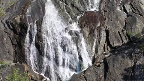 A powerful waterfall cascades down a rocky cliff face. Stock Footage 321998244