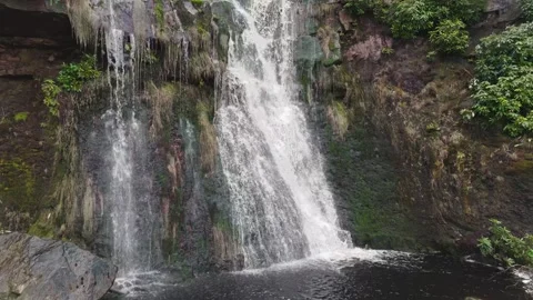 Powerful waterfall cascades down rugged, mossy rocks 库存影片 342928880