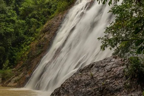 A powerful waterfall cascading down a steep, rocky cliff surrounded by lush, Stock Photos