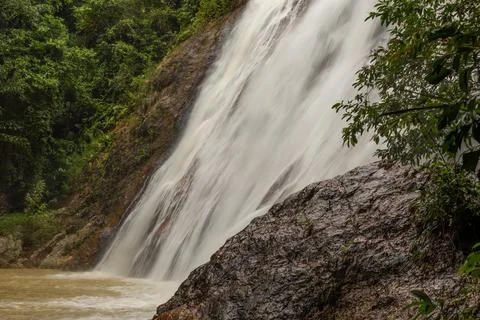 A powerful waterfall cascading down a steep, rocky cliff surrounded by lush, Stock Photos
