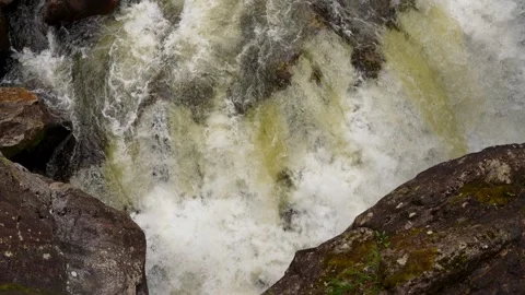 A powerful waterfall plunges over rugged rocks, creating a dramatic display of Stock Footage 313320397