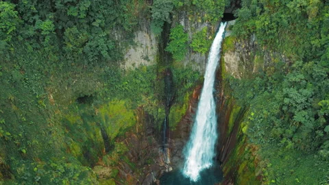Powerful waterfall plunges into a turquoise pool through vivid cliffs in Blue Stock Footage 311964392