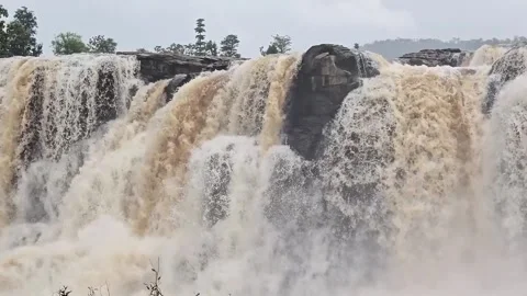 A powerful waterfall rushing over a rocky cliff during the monsoon season. 스톡 동영상 342047477