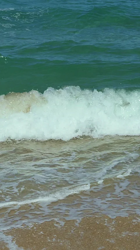 A powerful wave crashes onto a sandy shore, showcasing the ocean's raw energy Stock-Footage 305041805