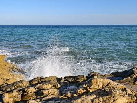 Powerful waves break against rocky shoreline, vivid turquoise waters clash with Stock Photos