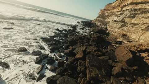 Powerful waves pound dark rocks at cliffside Stock Footage 339792037