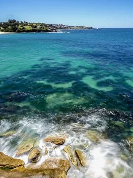 Powerful white waves (blurred motion) crashing into rocky coastline Stock Photos