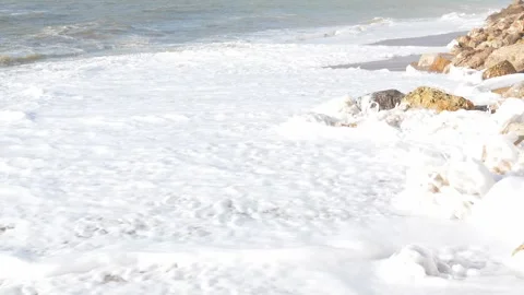 Powerful white waves rolling over golden rocks, with serene coastal tranquility 库存影片 308706425