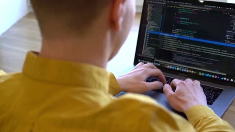 Pprogrammer in a yellow shirt typing code on the keyboard Stock Footage 142400965