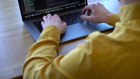 Pprogrammer in a yellow shirt typing code on the keyboard Stock Footage 142400966