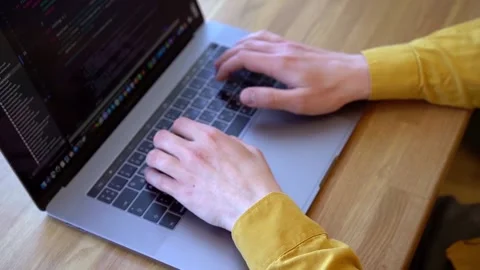 Pprogrammer in a yellow shirt typing code on the keyboard Stock Footage 142400981