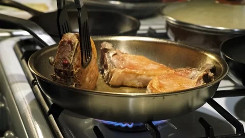 Practical cooking tutorial: frying chicken in a metallic pan on a gas stove in Stock Footage 338323854