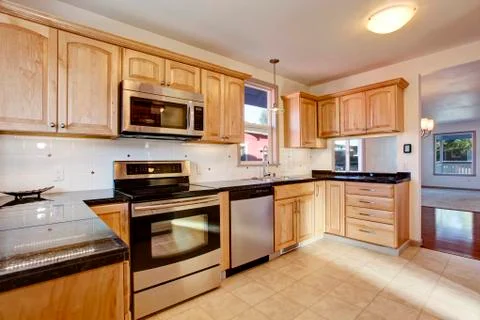 Practical kitchen room with light tones cabinets, steel appliances, black gra Stock Photos