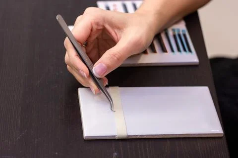 Practice eyelash extension on tile .Artificial lashes,Work with tweezer Stock Photos