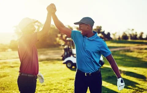 Practice winning every day. two golfers high-fiving on a golf course. Stock Photos