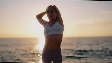 Practice yoga at sunset on a sandy beach by the sea. A woman performs gentle Stock Footage 303693018