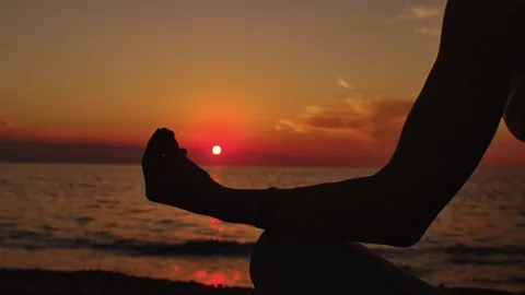 Practice yoga at sunset on a sandy beach by the sea. A woman performs gentle Stock Footage 303693152