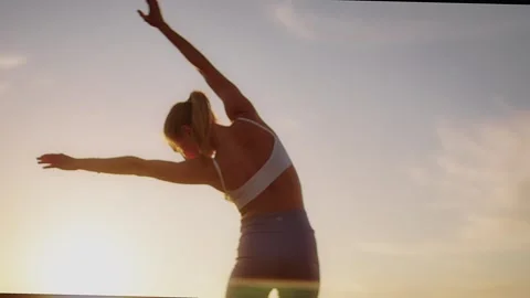 Practice yoga at sunset on a sandy beach by the sea. A woman performs gentle Stock Footage 303693445