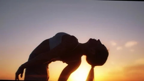 Practice yoga at sunset on a sandy beach by the sea. A woman performs gentle Stock Footage 303693700