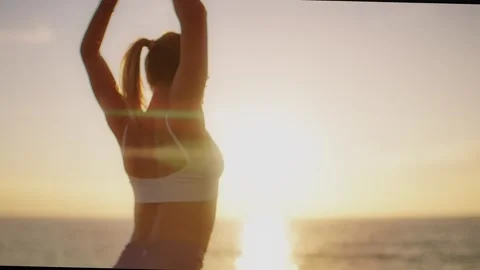 Practice yoga at sunset on a sandy beach by the sea. A woman performs gentle Stock Footage 303693717