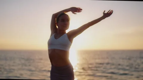 Practice yoga at sunset on a sandy beach by the sea. A woman performs gentle Stock Footage 303693784